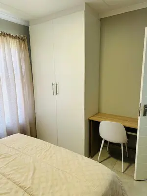 a bedroom with a bed and a desk and a chair at Homely Stay 2 in Kempton Park
