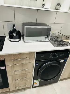 a kitchen with a microwave and a washer and dryer at Homely Stay 2 in Kempton Park