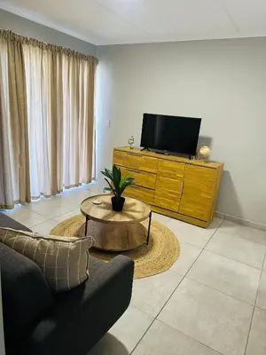 a living room with a tv and a couch and a table at Homely Stay 2 in Kempton Park
