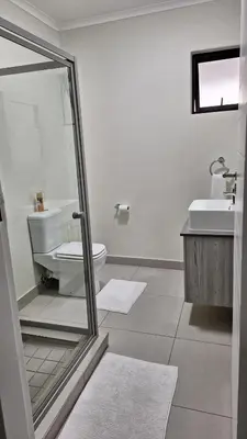 a white bathroom with a toilet and a sink at The Luxury Apartments in Midrand