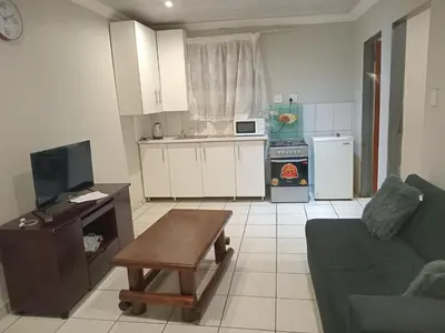 a kitchen and living room with a couch and a table at Kama house in Pretoria