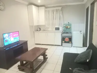 a kitchen with a table and a tv in a room at Kama house in Pretoria