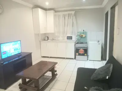 a kitchen with a couch and a table and a television at Kama B&B in Pretoria