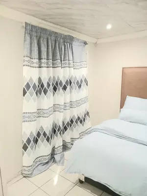 a bedroom with a bed and a curtain at Kama B&B in Pretoria