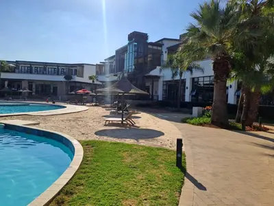 a resort with a pool and palm trees and buildings at Kayalako at theBlyde 1 in Pretoria