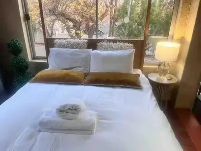 a large bed with white sheets and pillows and a window at Executive loft at Brooklyn in Pretoria