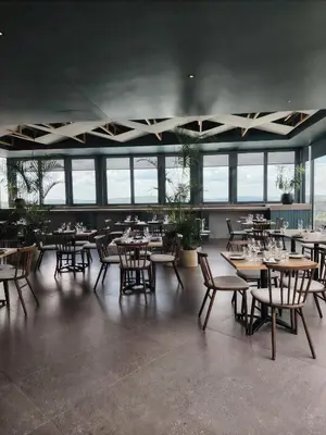a dining room with tables and chairs and windows at Menlyn Maine Trilogy Apartment 1101 in Pretoria