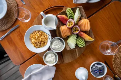 a wooden table with a plate of food and glasses of wine at Tshwene Lodge in Welgevonden Game Reserve