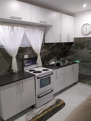 a kitchen with white cabinets and a stove top oven at Millenium Manor Executive Homes in Centurion