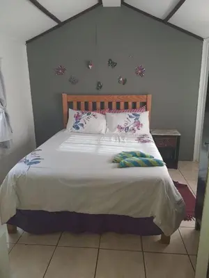 a bedroom with a large bed with pillows on it at Chalet 1 Camping Style at Cynthias Country Farmstay Outside bathroom in Hartbeespoort