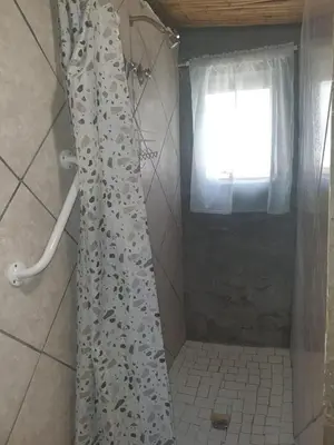 a shower curtain in a bathroom with a window at Chalet 2 Camping Style at Cynthias Country Outside bathrooms in Hartbeespoort