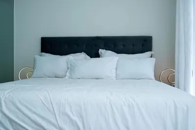 a white bed with a black headboard and white pillows at Feelathome in Midrand
