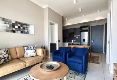 a living room with a couch and blue chairs and a table at Menlyn Maine Trilogy Collection in Pretoria