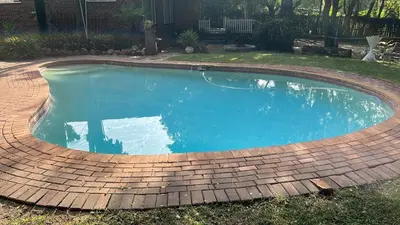 a swimming pool with a brick border around it at Cottage 2 at Cynthias Country in Hartbeespoort