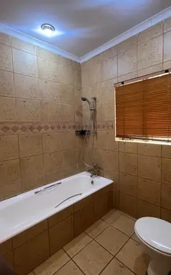 a bathroom with a bath tub and a toilet at Windsor villa in Pretoria