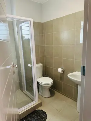 a bathroom with a toilet and a glass shower at Calm & Cozy Apartment in Pretoria