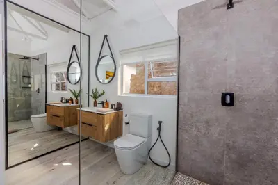 a bathroom with a toilet and two sinks and a shower at Enso Botanico Boutique Villa, Kosmos in Hartbeespoort