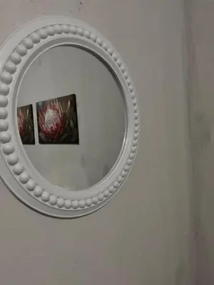 a mirror on a wall with a picture in it at BEGIN GUESTHOUSe in Ermelo