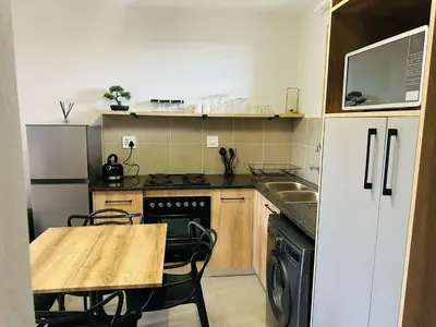 a small kitchen with a wooden table and a counter top at Calm & Cozy Apartment 2 in Pretoria