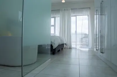 a white bedroom with a bed and a large window at Fealathome Two Bedroom in Midrand