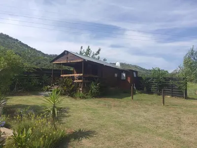 a wooden cabin in a field with a fence at Chalet 5 At Cynthias Country in Hartbeespoort