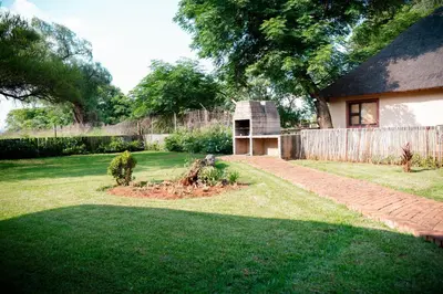 a yard with a house and a brick path at Falcon Lodge Bela in Bela-Bela