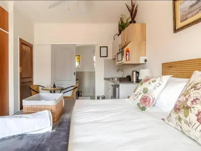 a bedroom with a white bed and a kitchen at Amalfi Place in Pretoria