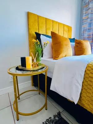 a bed with a yellow headboard and a table at The Blyde Lagoon in Pretoria
