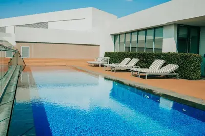 a swimming pool with two lounge chairs and a building at Menlyn Maine Trilogy 1417 in Pretoria
