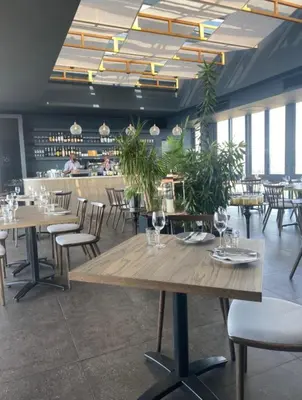 a dining room with tables and chairs and plants at Menlyn Maine Trilogy 1417 in Pretoria