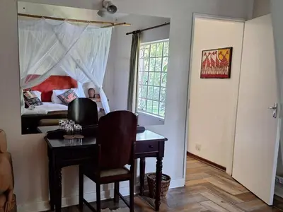 a bedroom with a desk and a bed and a window at Seringa Lodge & Safaris in White River