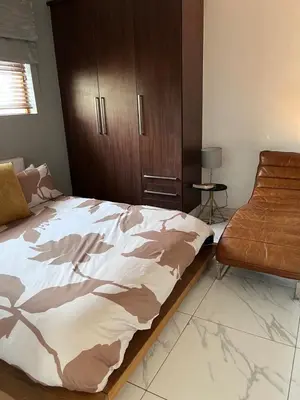a bedroom with a bed and a chair at Cosy 3 bedroom apartment In Pretoria East in Pretoria