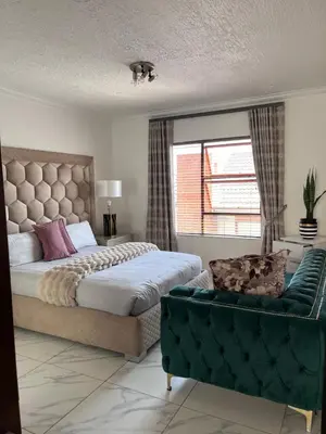 a bedroom with a bed and a couch and a window at Cosy 3 bedroom apartment In Pretoria East in Pretoria