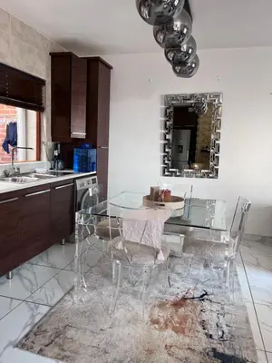 a kitchen with a glass table and some chairs at 3 bedroom holiday apartment in Pretoria East in Pretoria