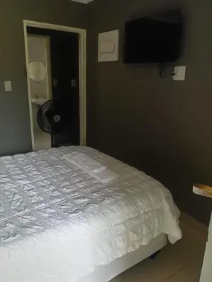 a bedroom with a bed and a television on the wall at Crystal Park Guest House in Benoni