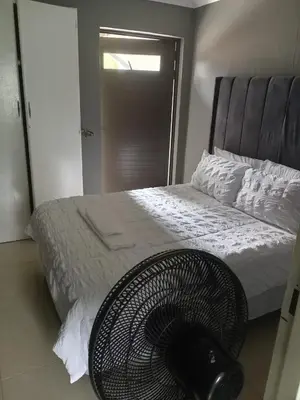 a bedroom with a bed with a fan next to it at Crystal Park Guest House in Benoni