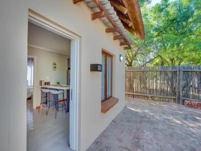 an open door to a patio with a table and a fence at Zebula 1 Pela Lodge, 6 bedrooms in Warmbaths