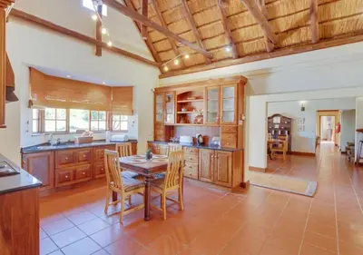 a kitchen with wooden cabinets and a table and chairs at Zebula 1 Pela Lodge, 6 bedrooms in Warmbaths