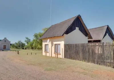 a small house with a fence next to a field at Zebula 1 Pela Lodge, 2-bedroom cottage in Warmbaths