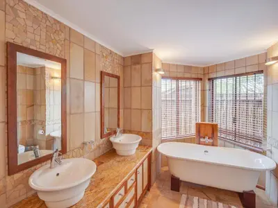 a large bathroom with two sinks and two mirrors at 210 Zebula, 5-bedroom house & 1-bedroom cottage in Warmbaths
