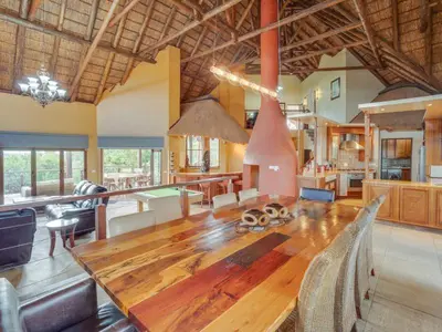 a large living room with a wooden table and a kitchen at 210 Zebula, 5-bedroom villa in Warmbaths