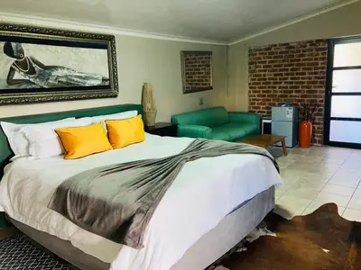 a bedroom with a large bed and a couch at Urban Space Lodge in Pretoria