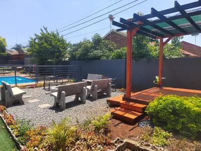 a patio with benches and a wooden pergola at Palma Royal Ensuite in Pretoria