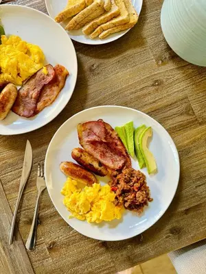 three plates of breakfast food on a wooden table at Grey Villa on Orion- Luxury Apartment in Polokwane
