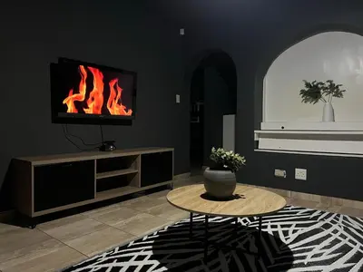 a living room with a table and a fire fireplace at Grey Villa on Orion- Luxury Apartment in Polokwane