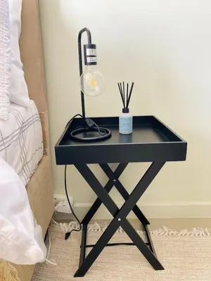 a black table with a lamp on it next to a bed at The Minimalist Hideout in Erand