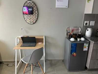 a table and a desk with a laptop on top of a refrigerator at Peaceful Cute Apartment in Pretoria