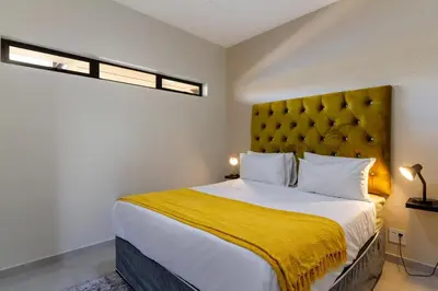 a bedroom with a large bed with a yellow blanket at #AlimamaSpaces The Manson's Kyalami Woods in Midrand