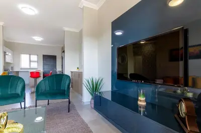 a living room with a large tv on a blue wall at #AlimamaSpaces The Rob's Kyalami Woods in Midrand