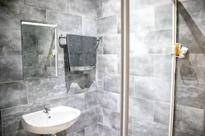 a gray tiled bathroom with a sink and a mirror at Glow Events &Guest House in Centurion